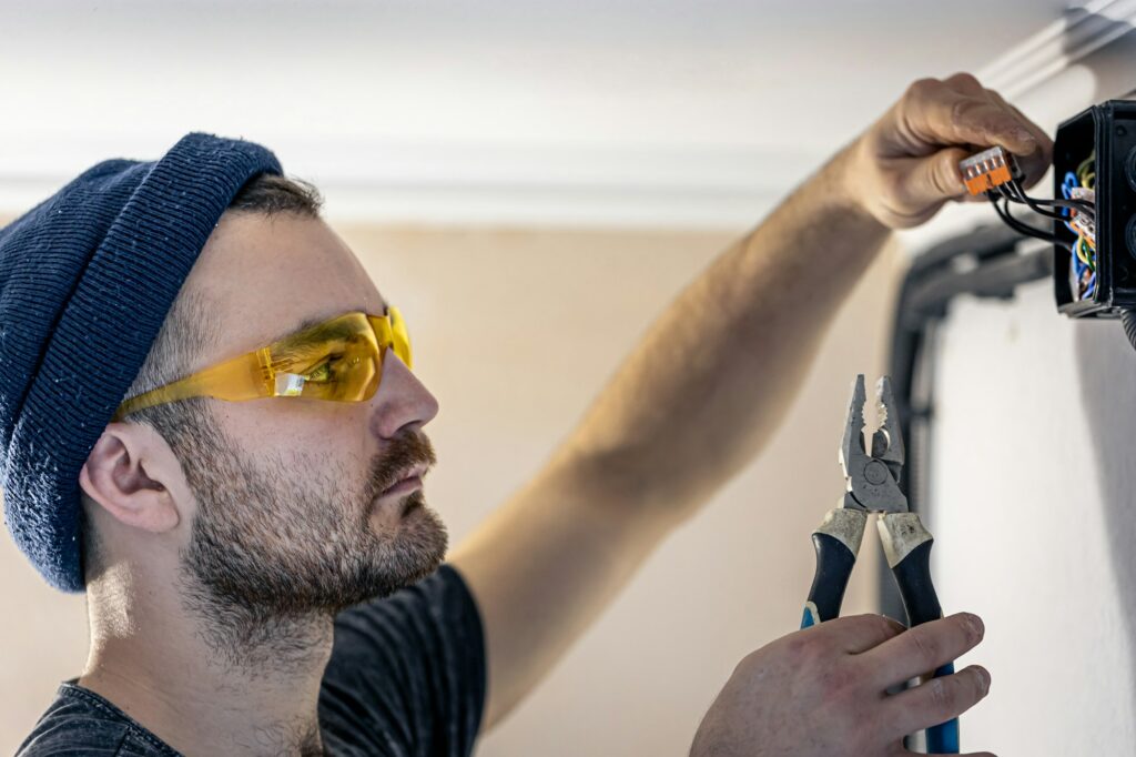 An electrician is mounting electric sockets on the white wall indoors.