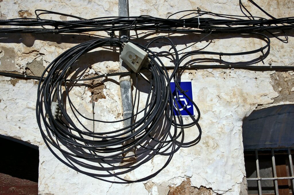 Bunch of wires hanging from the wall of an old building